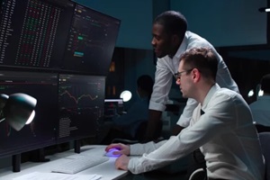 team of it programmers working on desktop computers in data center control room