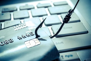 credit card phishing - piles of credit cards with a fish hook on computer keyboard